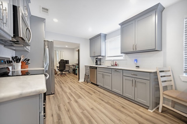 kitchen featuring appliances with stainless steel finishes, gray cabinetry, and sink