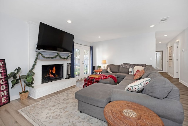 living room with wood-type flooring and a brick fireplace