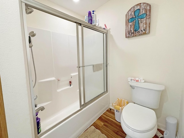 bathroom featuring shower / bath combination with glass door, hardwood / wood-style floors, and toilet