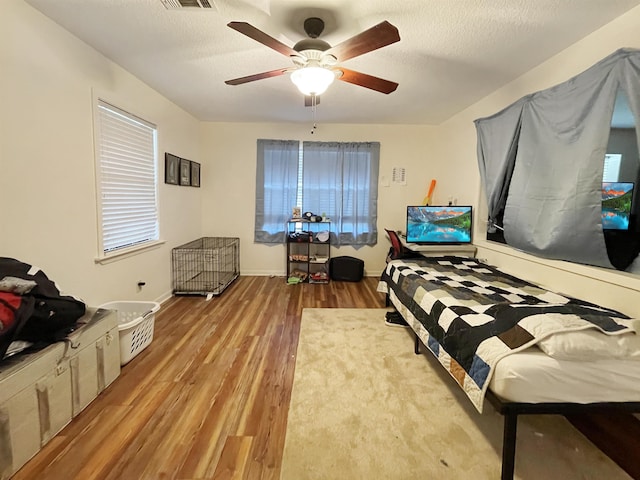 bedroom featuring hardwood / wood-style floors, a textured ceiling, and ceiling fan