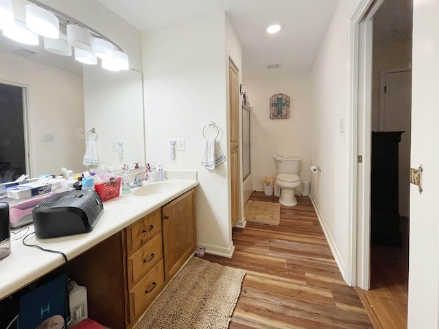 full bathroom with bath / shower combo with glass door, vanity, wood-type flooring, and toilet