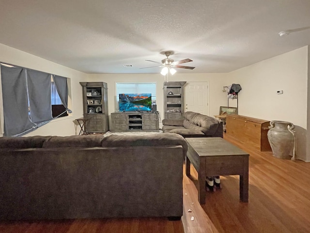 living room with hardwood / wood-style floors, ceiling fan, and a textured ceiling