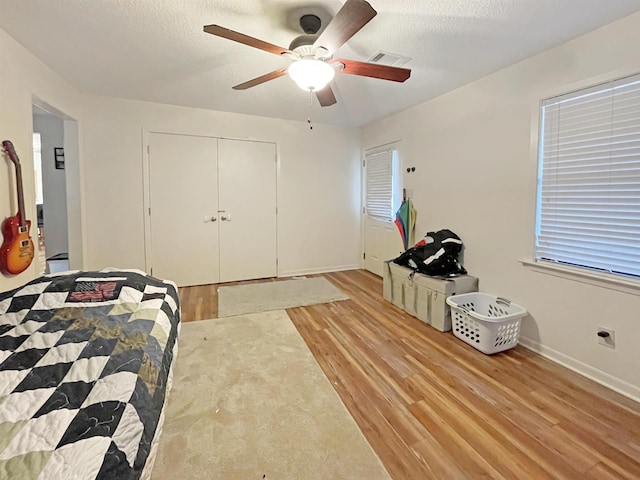 bedroom featuring ceiling fan, light hardwood / wood-style floors, a textured ceiling, and a closet