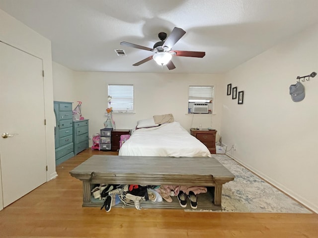 bedroom featuring ceiling fan, cooling unit, and light hardwood / wood-style floors