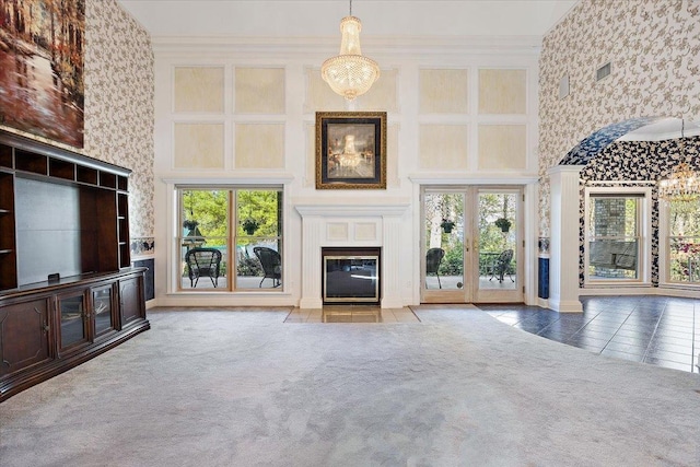 unfurnished living room featuring a towering ceiling, a healthy amount of sunlight, and a notable chandelier