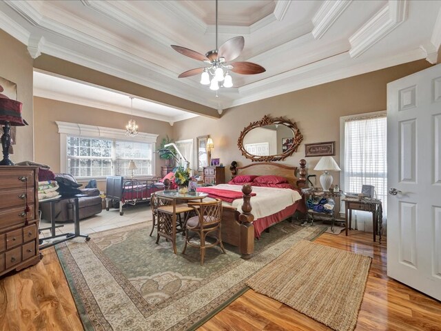 bedroom with a tray ceiling, multiple windows, crown molding, and wood finished floors