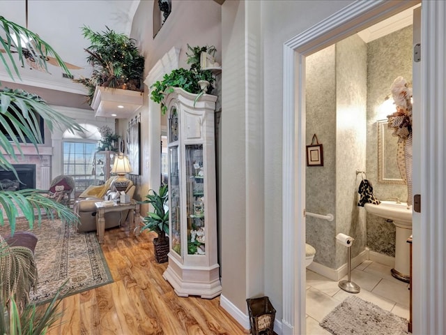 interior space with a fireplace, a sink, wood finished floors, baseboards, and ensuite bath
