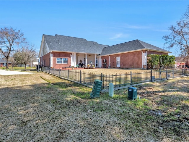 view of front facade with fence private yard, a front yard, a patio, and brick siding