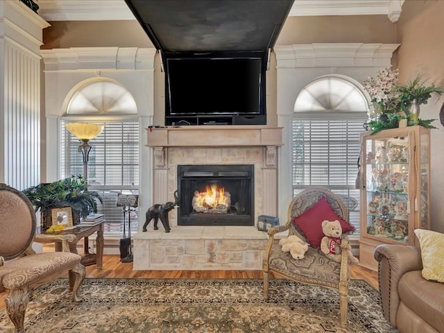 sitting room featuring a lit fireplace, ornamental molding, and wood finished floors