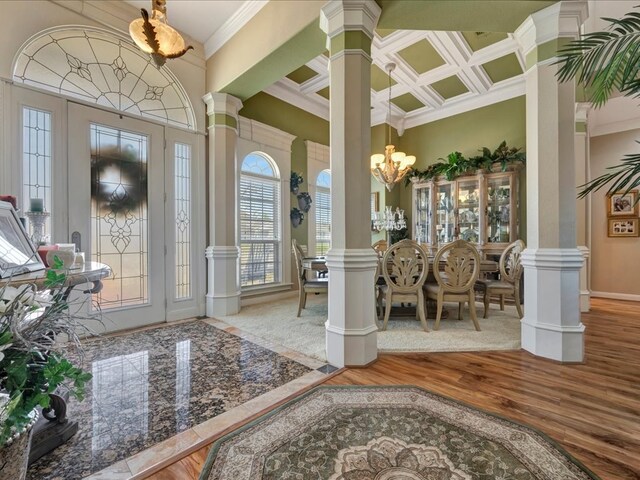 entryway featuring decorative columns, coffered ceiling, ornamental molding, wood finished floors, and an inviting chandelier