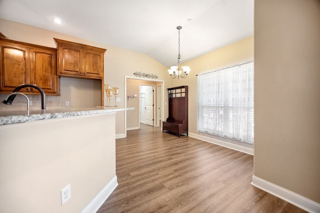 113 Westfield Loop, Lufkin, TX 75904 - kitchen featuring a chandelier, vaulted ceiling, brown cabinets, wood finished floors, and hanging light fixtures