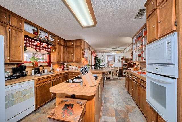 2105 Carters Ferry Rd, E Road, Milam, TX 75959 - kitchen featuring white appliances, a textured ceiling, stone finish floor, visible vents, and a sink