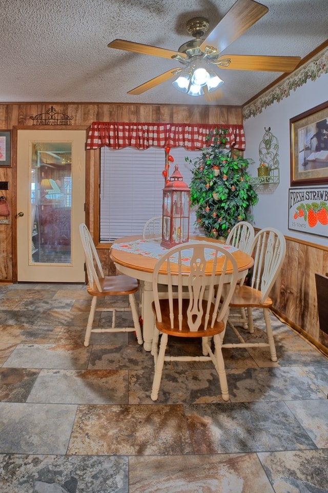 2105 Carters Ferry Rd, E Road, Milam, TX 75959 - dining room featuring wooden walls, ceiling fan, stone tile floors, and a textured ceiling