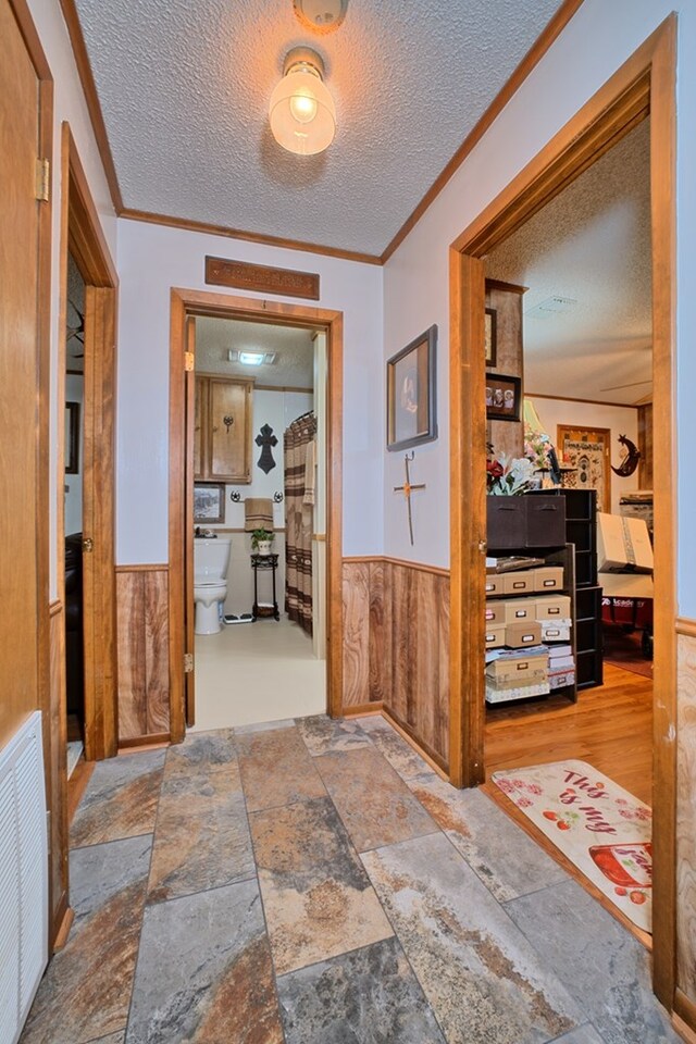 2105 Carters Ferry Rd, E Road, Milam, TX 75959 - corridor featuring crown molding, a textured ceiling, visible vents, wainscoting, and wooden walls