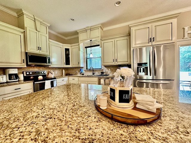 4815 Fm 2827, Warren, TX 77664 - kitchen featuring stainless steel appliances, light stone countertops, decorative backsplash, cream cabinets, and ornamental molding