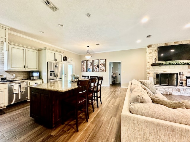 4815 Fm 2827, Warren, TX 77664 - kitchen featuring stainless steel appliances, open floor plan, wood finished floors, a breakfast bar area, and crown molding