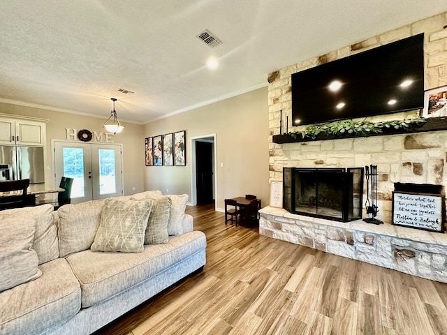 4815 Fm 2827, Warren, TX 77664 - living area with crown molding, wood finished floors, a stone fireplace, french doors, and a textured ceiling