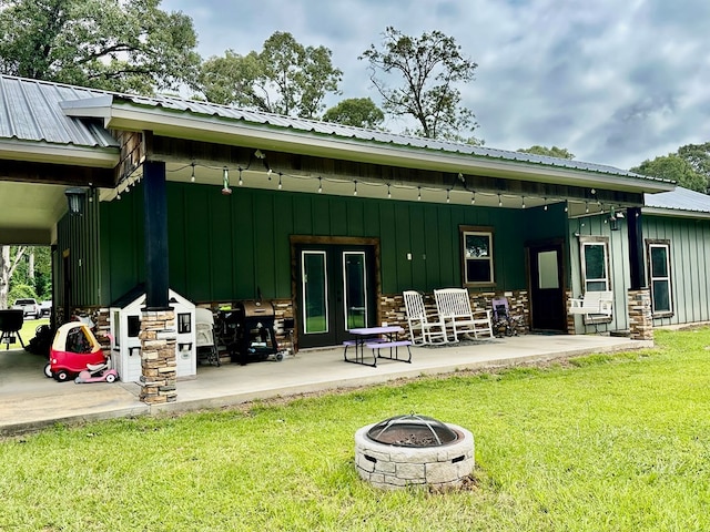 4815 Fm 2827, Warren, TX 77664 - rear view of property with board and batten siding, a yard, a fire pit, and metal roof