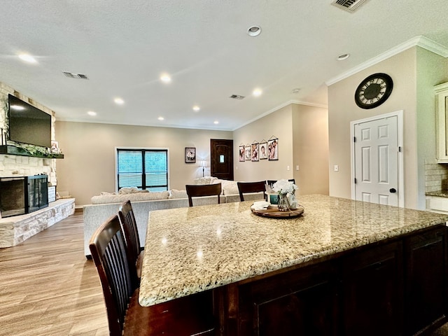 4815 Fm 2827, Warren, TX 77664 - kitchen with light wood-type flooring, open floor plan, light stone counters, a fireplace, and ornamental molding
