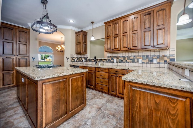 kitchen featuring light stone counters, a center island, hanging light fixtures, gas cooktop, and backsplash