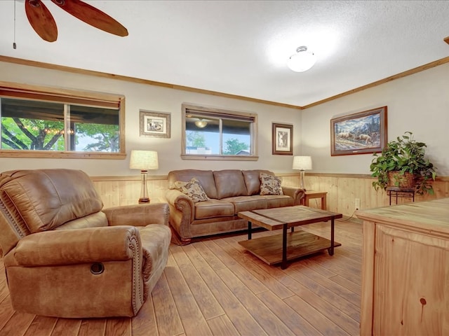 living room featuring a wealth of natural light, wooden walls, ornamental molding, and light wood-type flooring