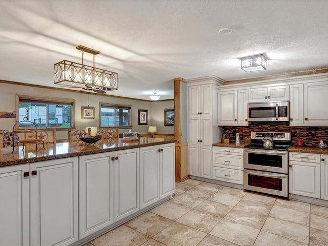 kitchen featuring pendant lighting, white cabinets, dark stone countertops, tasteful backsplash, and stainless steel appliances