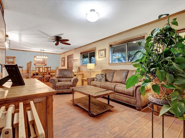 living room with ceiling fan, ornamental molding, a textured ceiling, and light hardwood / wood-style flooring