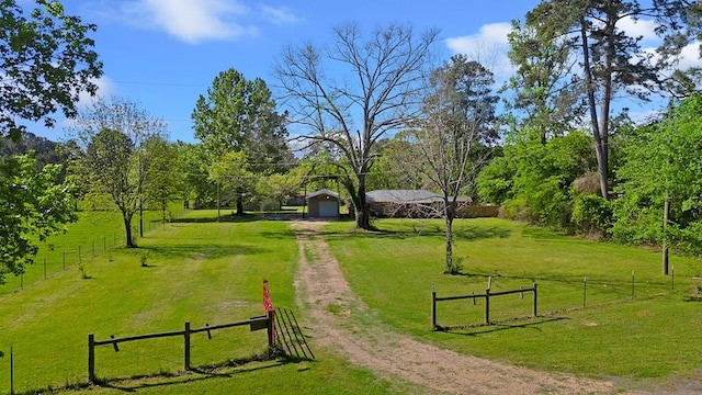 view of property's community featuring driveway, fence, a lawn, and a detached garage
