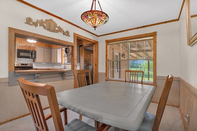 dining space featuring wooden walls, wainscoting, and crown molding
