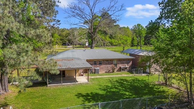 rear view of property with a patio, metal roof, fence, and a lawn