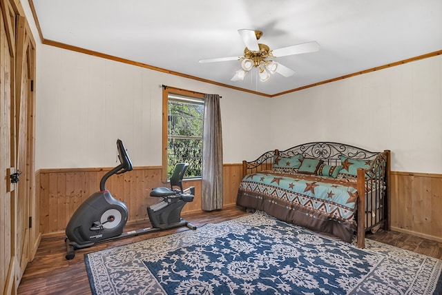 bedroom with wooden walls, crown molding, a wainscoted wall, and wood finished floors
