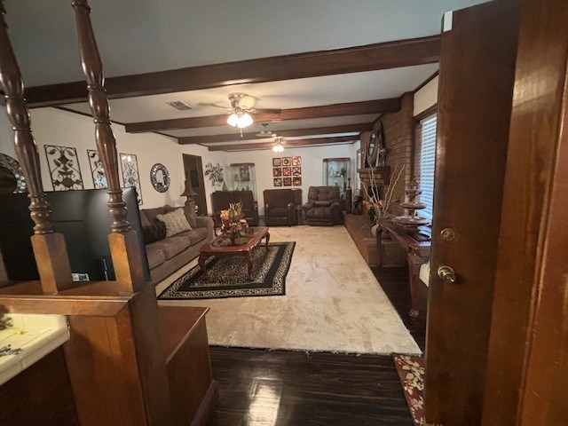 living room with beamed ceiling, dark hardwood / wood-style flooring, and ceiling fan