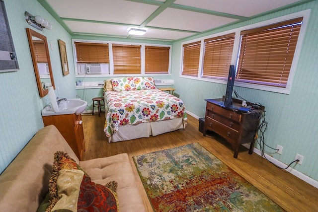 bedroom featuring baseboards, a sink, and wood finished floors