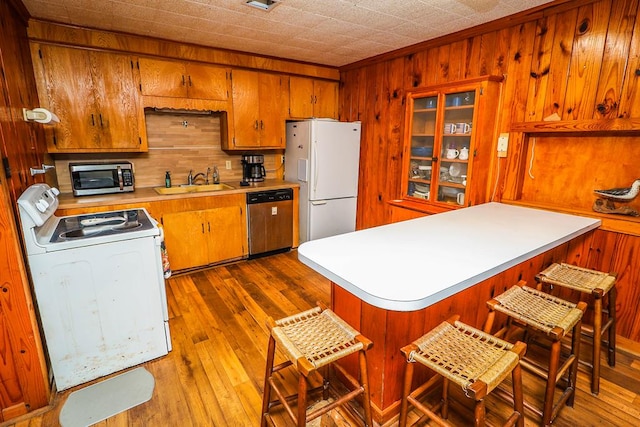 kitchen featuring brown cabinets, a sink, light countertops, dark wood-style floors, and stainless steel appliances