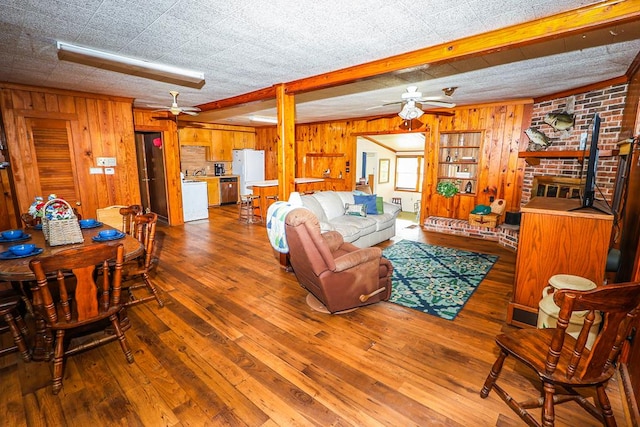 living room with ceiling fan, wooden walls, hardwood / wood-style flooring, and a fireplace