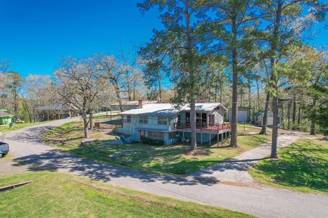 view of front of property with a garage, a front yard, a deck, a chimney, and driveway