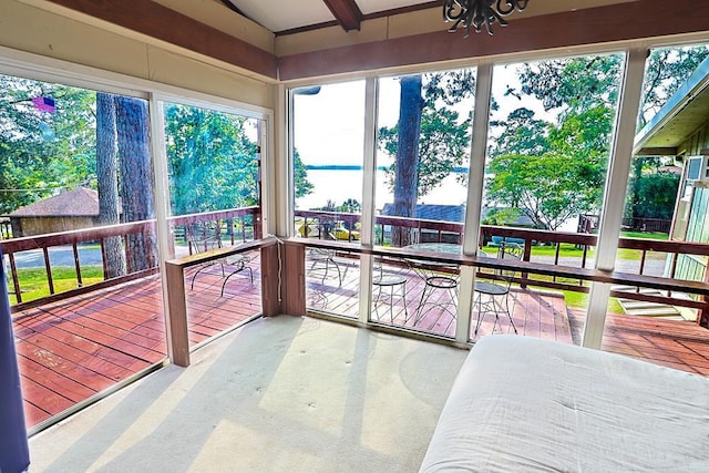sunroom with carpet floors and a deck with water view