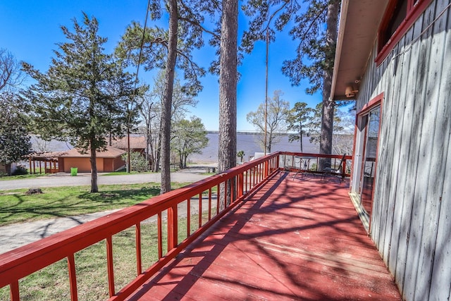 wooden terrace featuring a water view and a yard