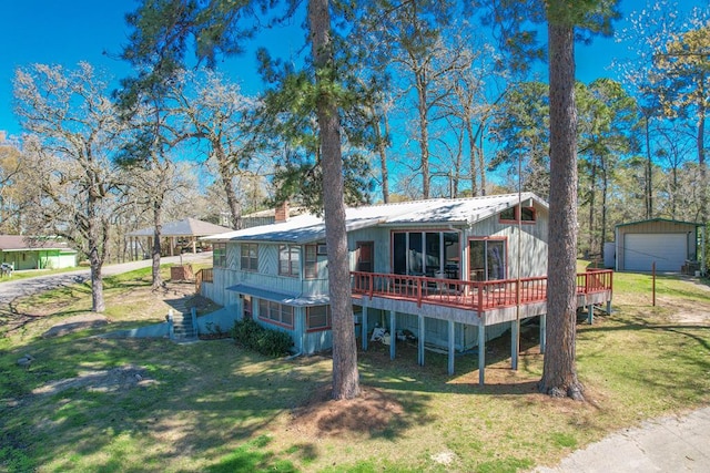 view of front of property featuring a detached garage, a deck, an outbuilding, and a front lawn