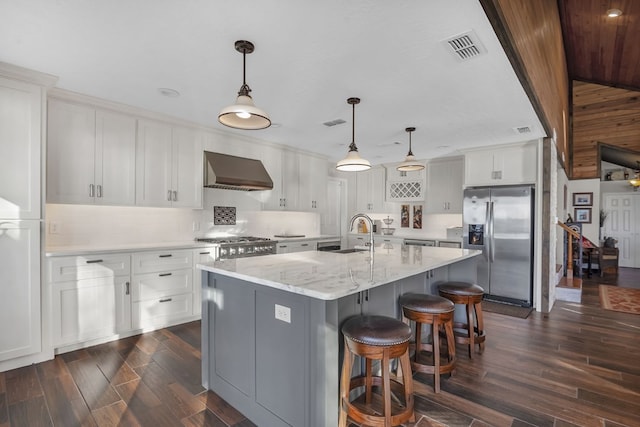 130 Boxwood Ln, Brookeland, TX 75931 - kitchen featuring stainless steel fridge with ice dispenser, wall chimney range hood, dark wood-style floors, white cabinetry, and a kitchen breakfast bar