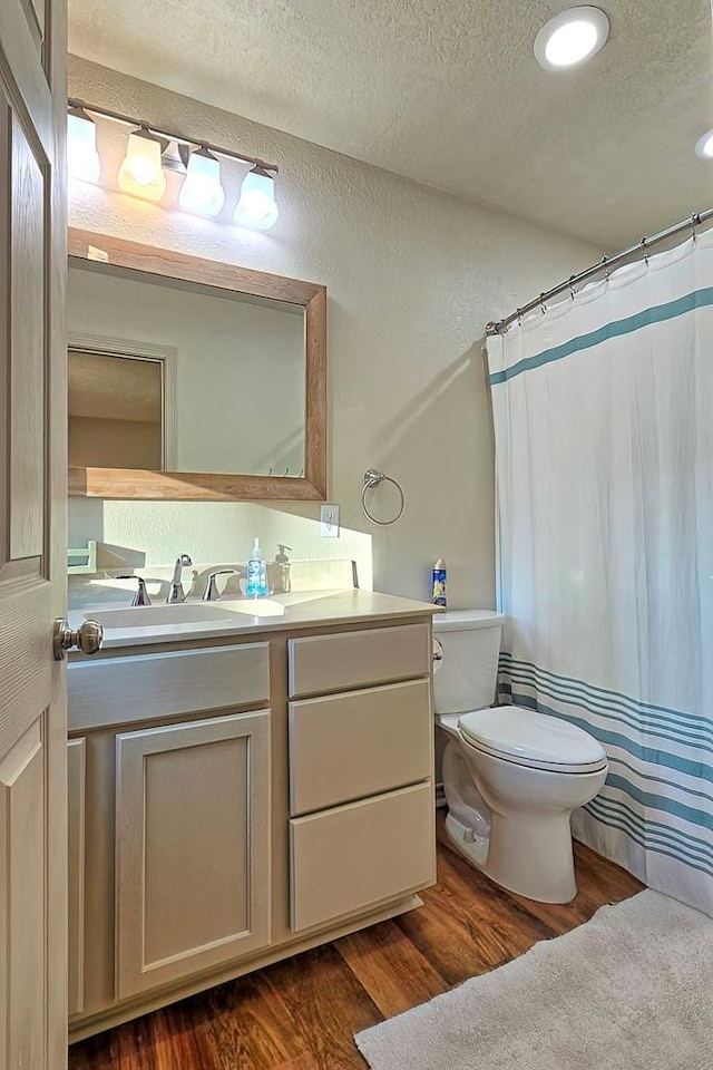 bathroom with hardwood / wood-style floors, vanity, a textured ceiling, and toilet