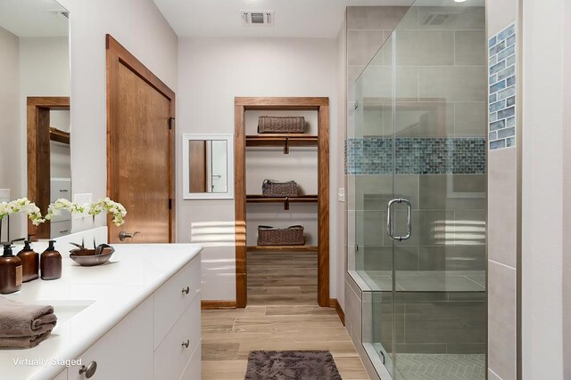 bathroom featuring hardwood / wood-style flooring, vanity, and an enclosed shower