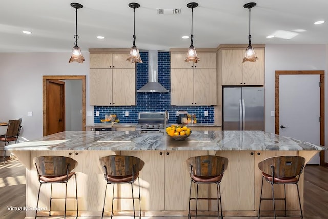 kitchen with light brown cabinetry, a kitchen island, and appliances with stainless steel finishes