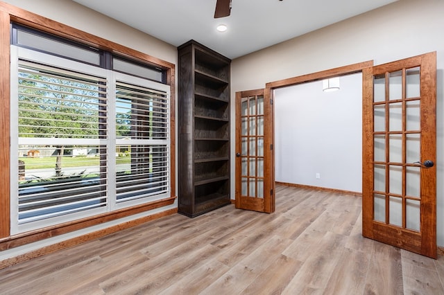 empty room featuring french doors, light hardwood / wood-style floors, and ceiling fan