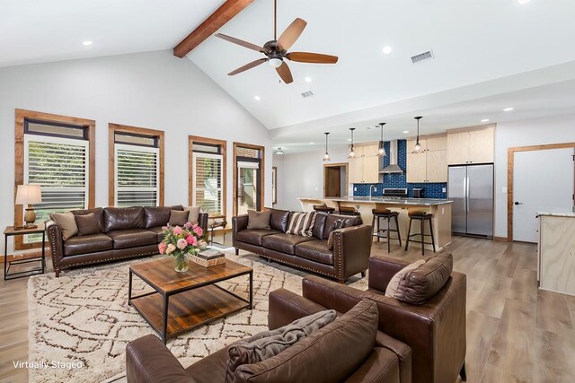 living room with ceiling fan, beam ceiling, light wood-type flooring, and a wealth of natural light