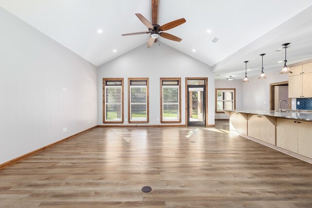 unfurnished living room with ceiling fan, sink, high vaulted ceiling, and light hardwood / wood-style flooring