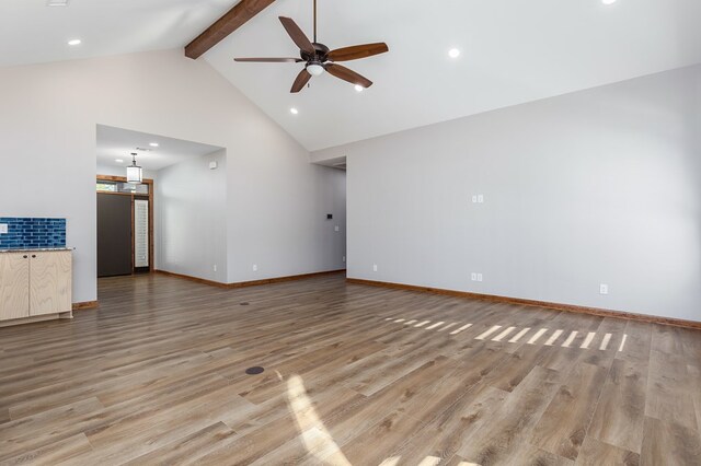 unfurnished living room featuring ceiling fan, light hardwood / wood-style flooring, beamed ceiling, and high vaulted ceiling