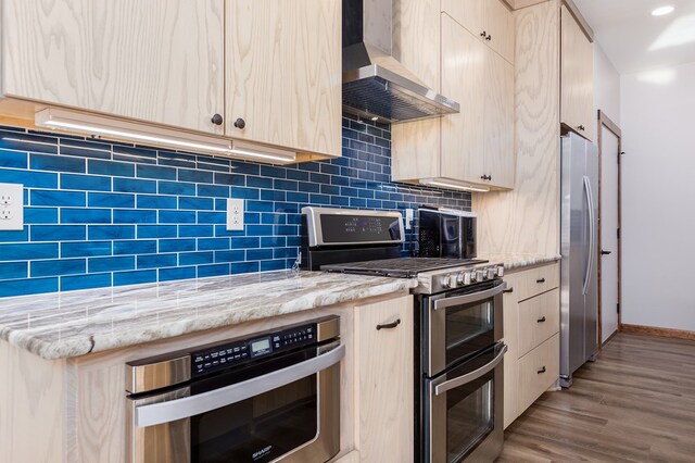 kitchen featuring appliances with stainless steel finishes, light wood-type flooring, light brown cabinets, and wall chimney range hood