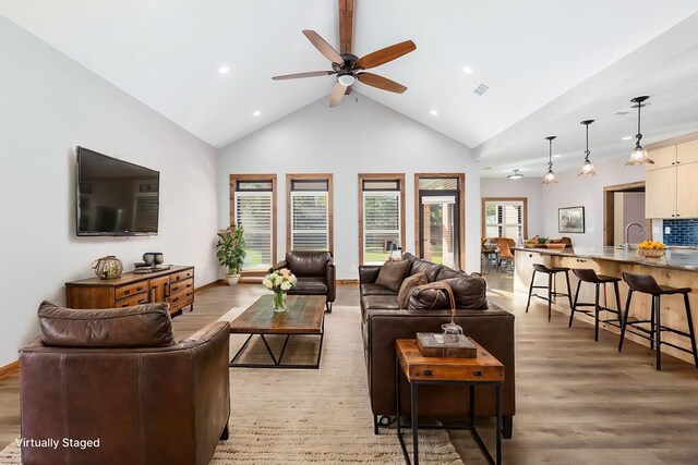 living room featuring ceiling fan, sink, high vaulted ceiling, and light wood-type flooring