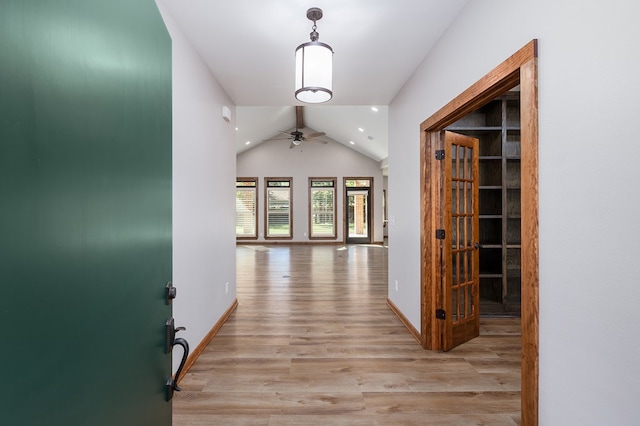 corridor with light hardwood / wood-style floors and vaulted ceiling